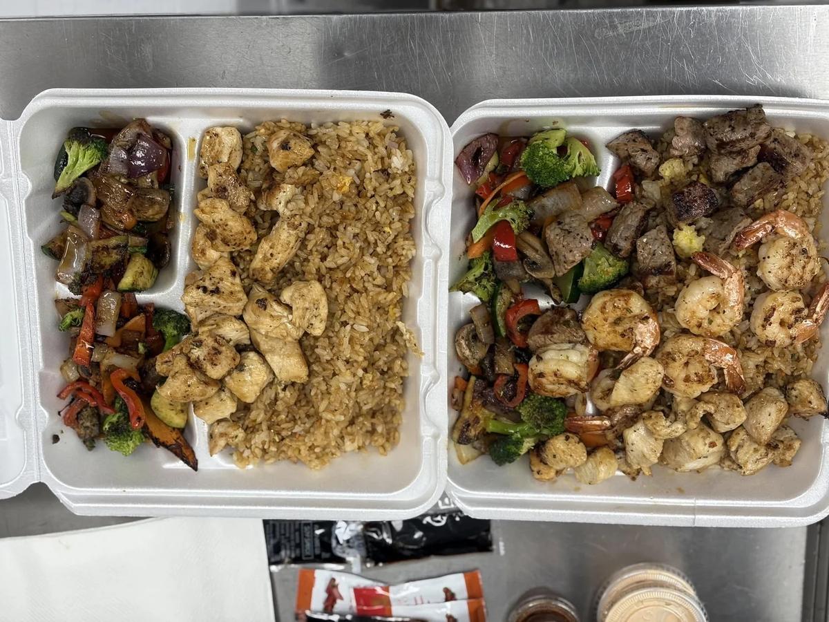 Two hibachi plates with fried rice, chicken, steak and vegetables